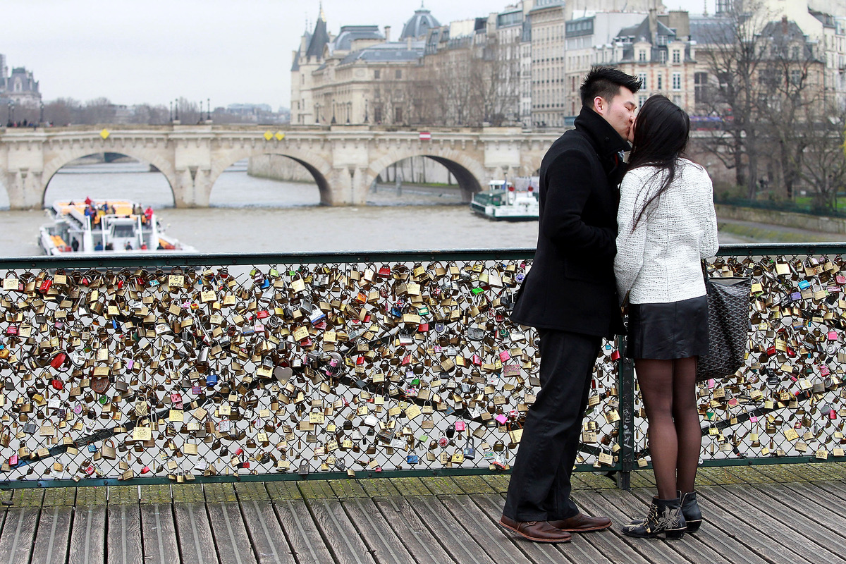 A couple is kissing on the Pont des Arts